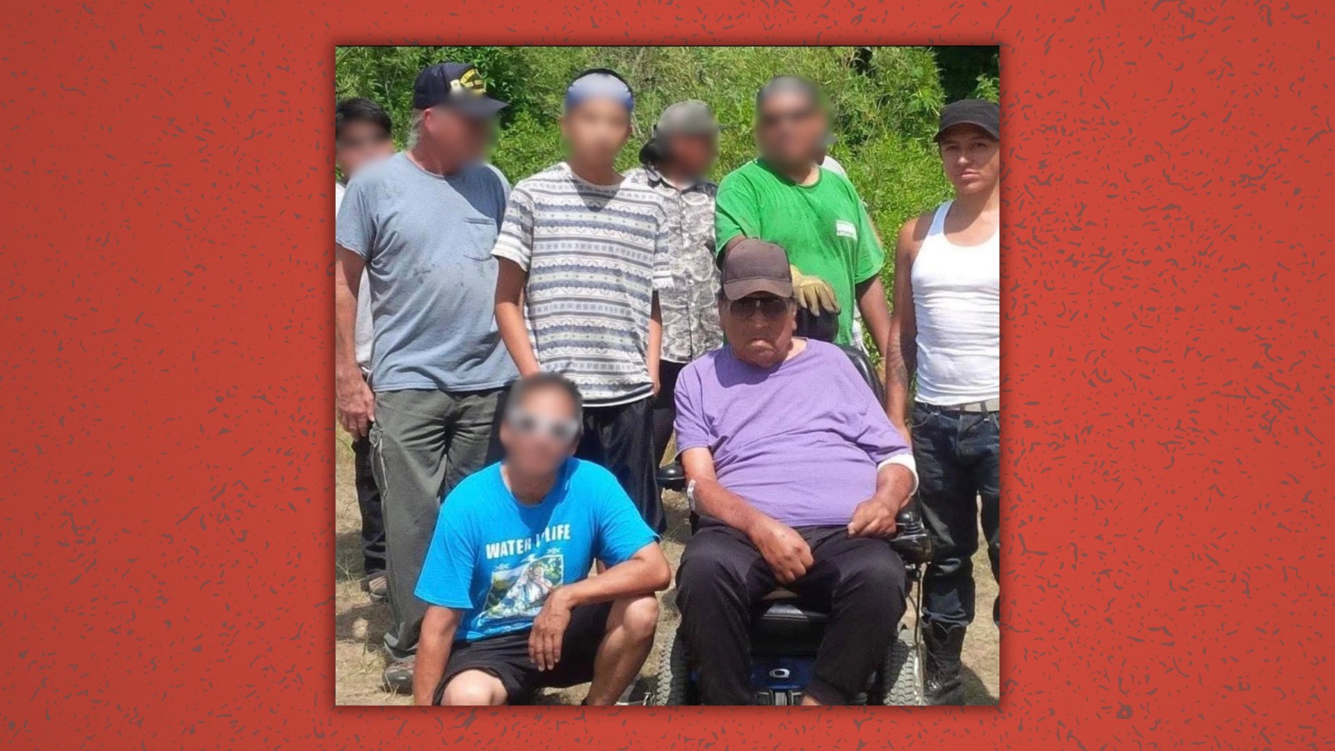A group photo outdoors: an elder seated in a wheelchair and a person standing at right; everyone else is blurred.